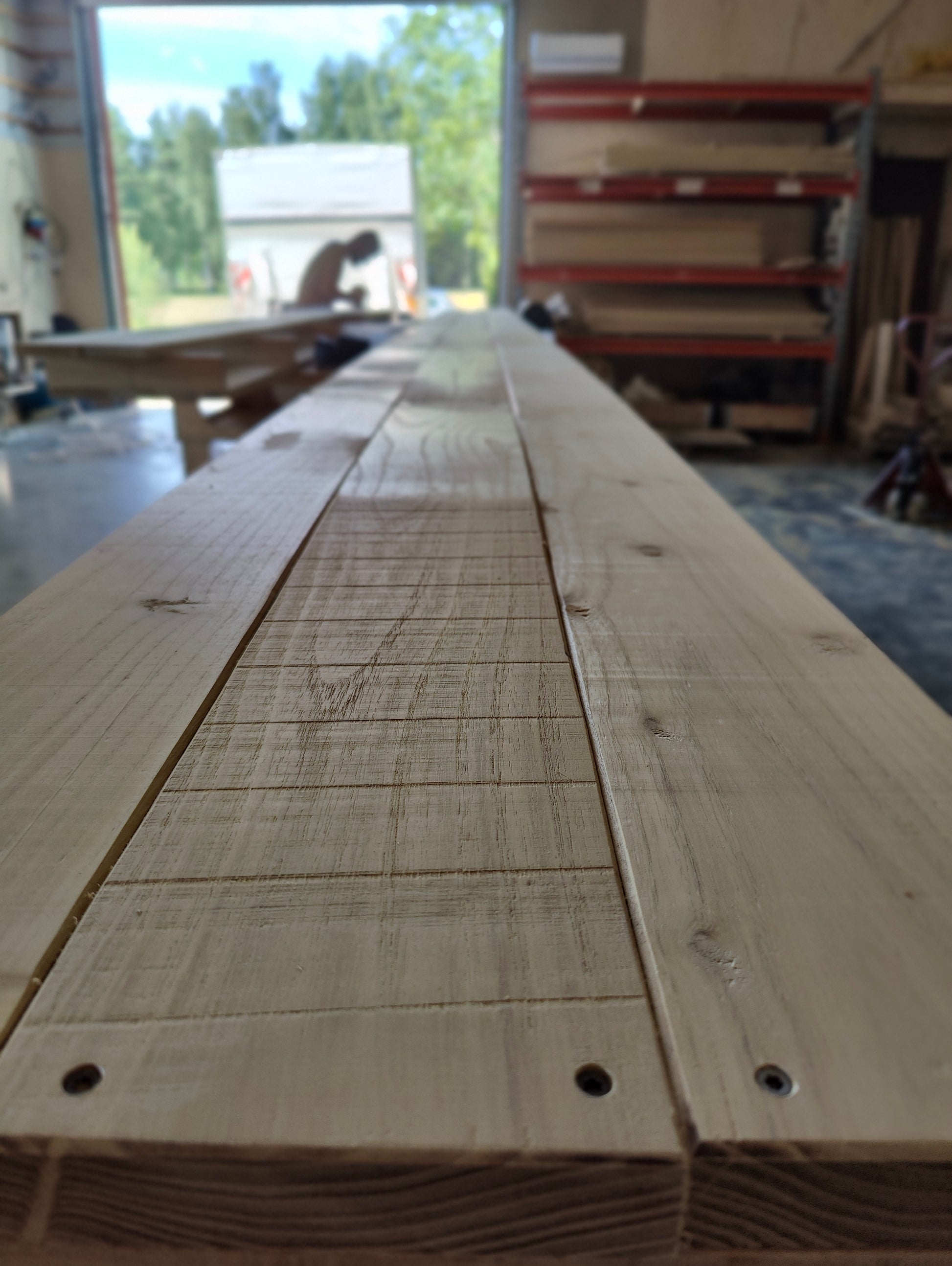 Long wooden planks with visible grain and markings in a workshop setting.