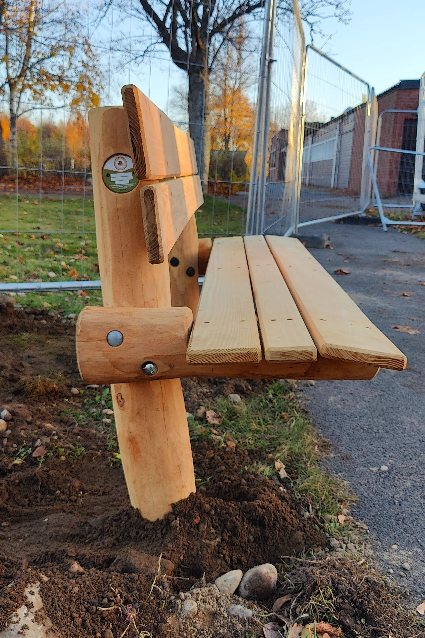Robinia träbänk förankrad i marken vid en stig i en park